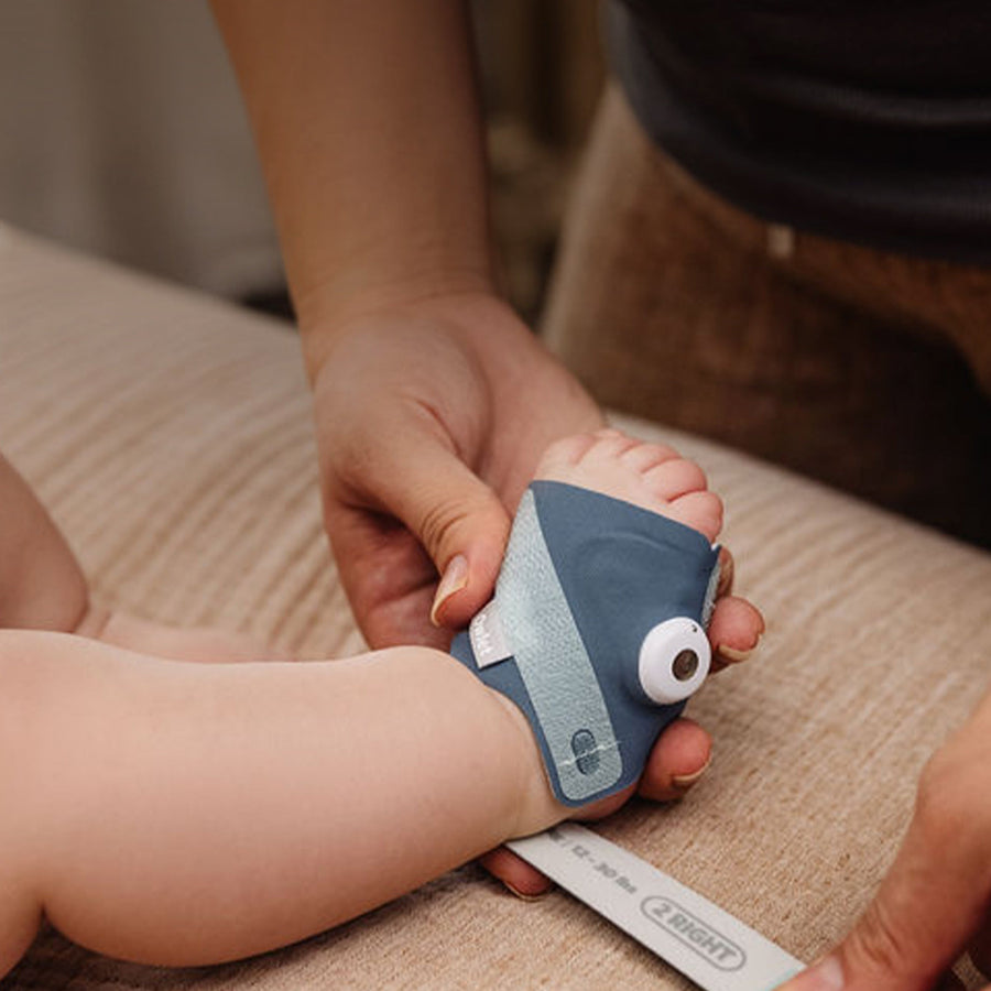 Een ouder doet een baby een stoffen sokje in Bedtime Blue aan